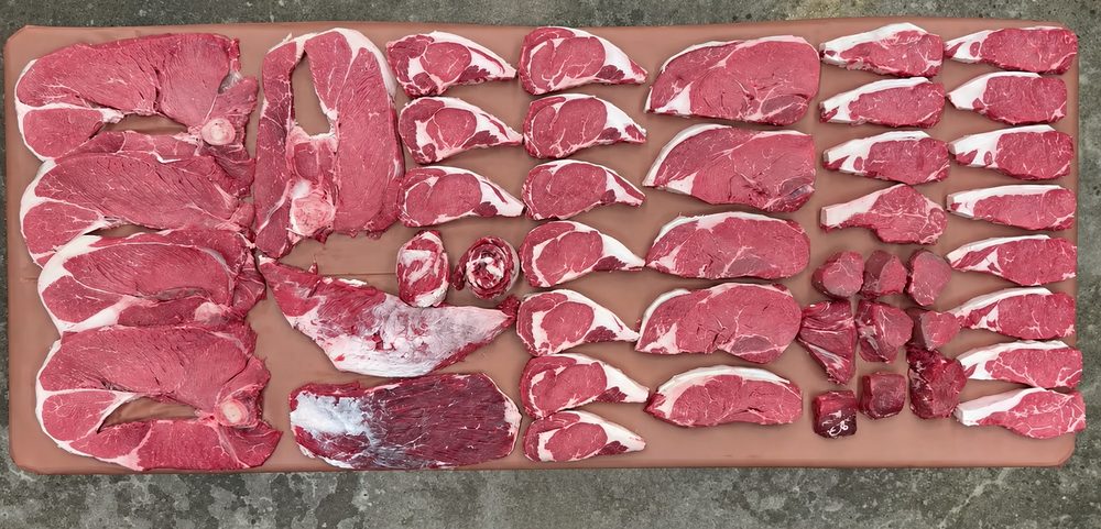 An eighth beef share laid out on the board: steaks, roasts and ground beef, seen from above